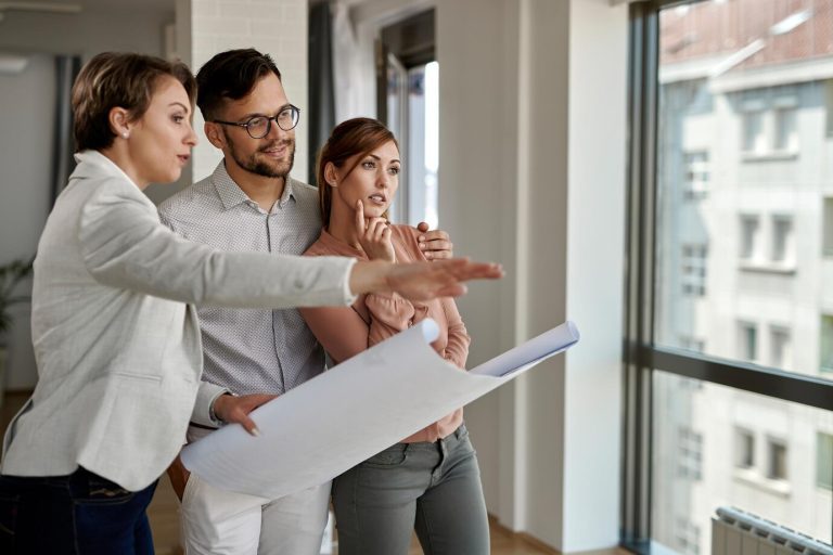 young-couple-examining-blueprints-with-real-estate-agent-while-buying-new-home_637285-6111